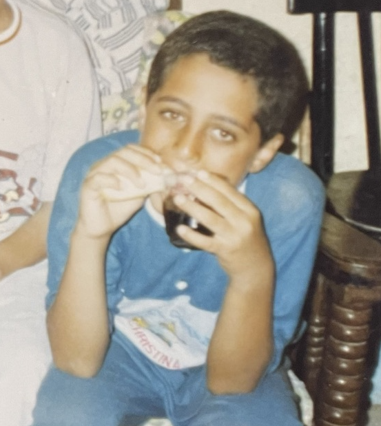 Young Mosab eating a sandwich and drinking a fizzy drink at the same time!